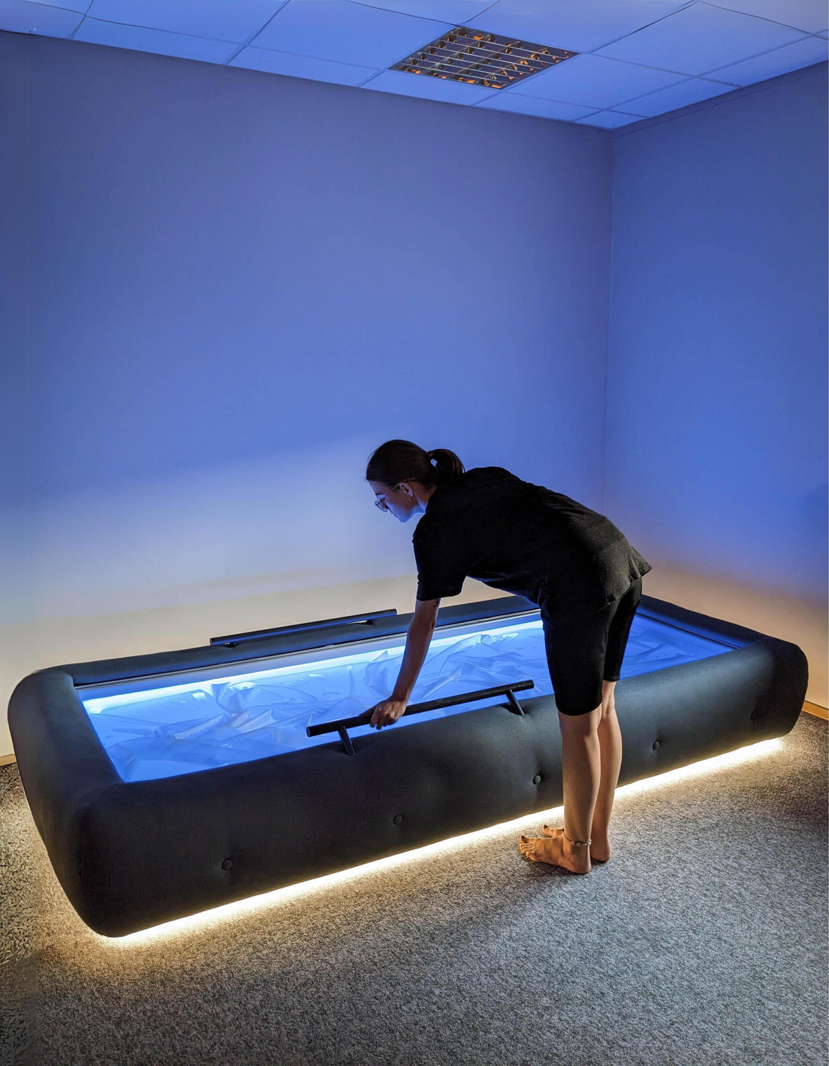 Person standing beside a dark upholstered Driifloat and holding the near support rail.