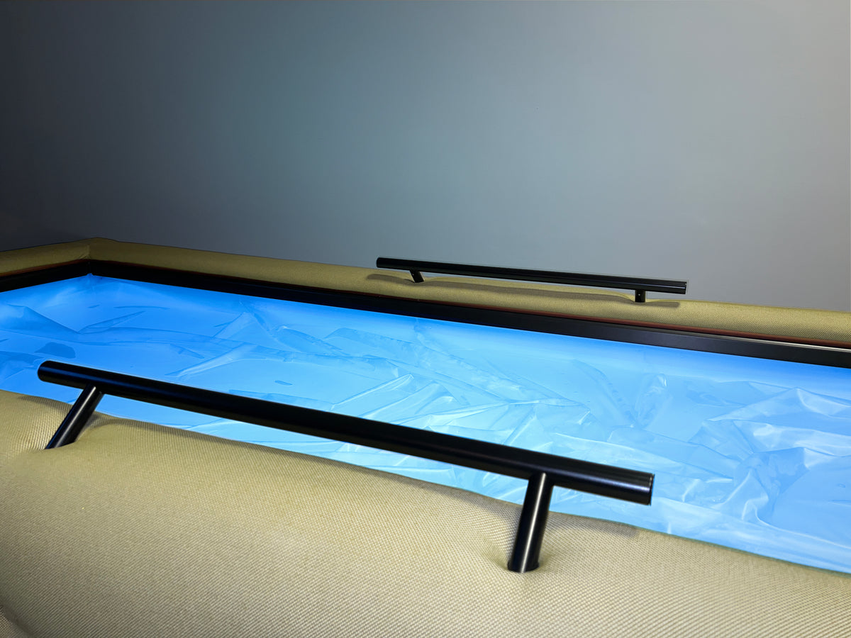 Close-up of a blue-lit Driifloat membrane with two black support rails and pale upholstered edges.